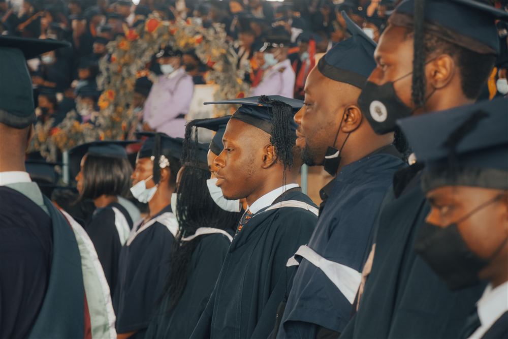 Men and women in graduation caps and gowns at a university ceremony